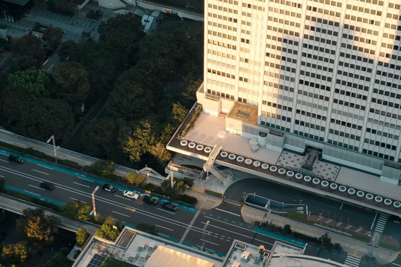 Aerial view of a highway and building entrance framed by trees in golden hour light