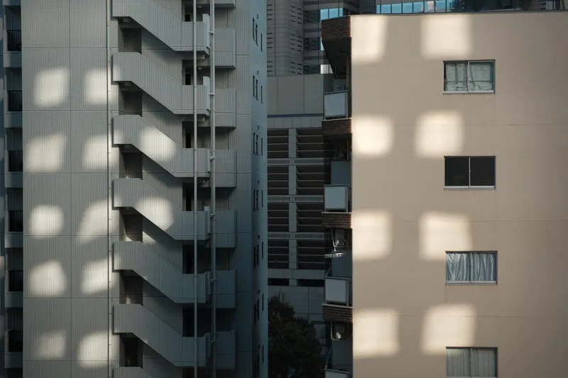 Afternoon sunlight casting geometric shadow patterns across apartment building balconies
