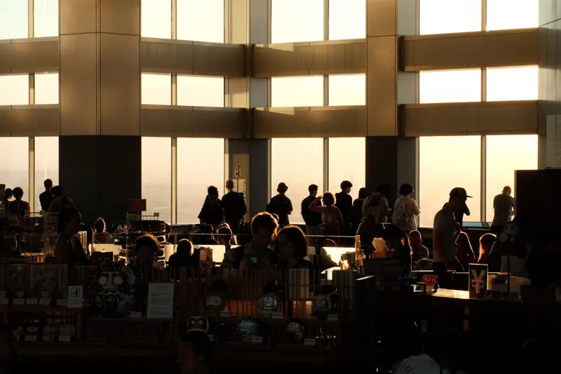 Silhouettes of visitors at an observation deck backlit by golden sunset light