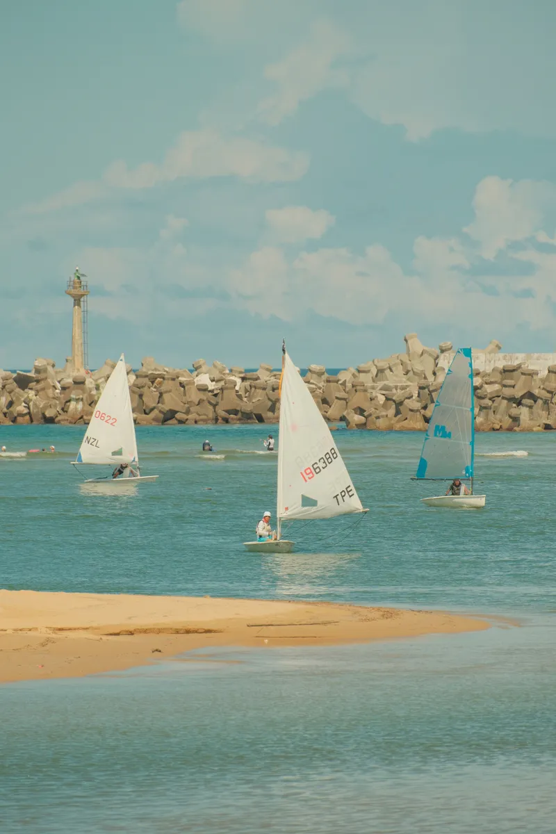 Sailboats racing near a breakwater with a lighthouse at Fulong Beach